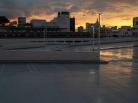 view from a roof over a parking lot under a cloudy sky at sunset with high rise buildings in the background