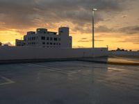 a parking lot at sunset in front of buildings with clouds, and an odd traffic sign