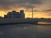 a parking lot at sunset in front of buildings with clouds, and an odd traffic sign