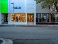 a retail store on a street corner next to a tree and a green sign that says dior