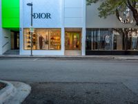 a retail store on a street corner next to a tree and a green sign that says dior