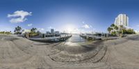 a fisheye lens photo of boats in a dock with buildings in the background with a beautiful blue sky