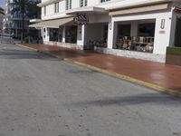 a very long building on the side of a road with benches in the middle of the street