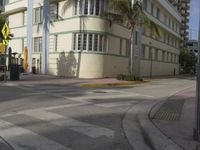 a city intersection with a street sign and a palm tree in the middle of the street