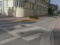 a city intersection with a street sign and a palm tree in the middle of the street