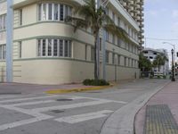 a city intersection with a street sign and a palm tree in the middle of the street