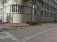 a city intersection with a street sign and a palm tree in the middle of the street