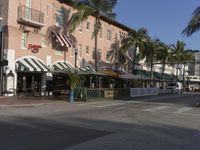 a city street lined with palm trees and shops and stores under some blue sky and sun