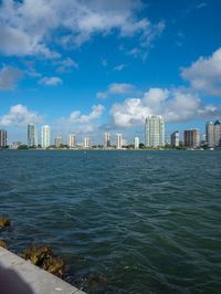 a city from the water's edge looking out to the other side, skyscrapers are visible in the background