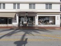 the street in front of the building has cars parked outside of it with chairs and tables