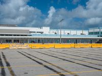 an empty parking lot filled with lots of buildings and trucks in the background of a cloudy blue sky