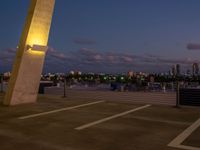 an outside view of a city skyline and a clock at sunset with lights on a pole