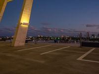 an outside view of a city skyline and a clock at sunset with lights on a pole