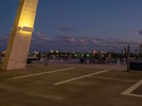 an outside view of a city skyline and a clock at sunset with lights on a pole