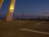 an outside view of a city skyline and a clock at sunset with lights on a pole