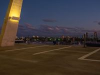 an outside view of a city skyline and a clock at sunset with lights on a pole