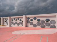 a white and grey wall with geometric designs on it on a red ground below the clouds