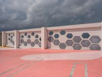 a white and grey wall with geometric designs on it on a red ground below the clouds