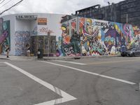 a large painting is on the side of a building with a large parking lot in front of it