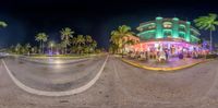 a 360 - view photo of an exterior and a street at night, featuring palm trees