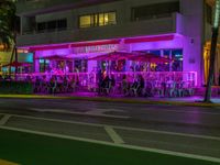 people sit under umbrellas at the bar next to an orange lit sidewalk with an umbrella in front