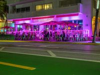 people sit under umbrellas at the bar next to an orange lit sidewalk with an umbrella in front