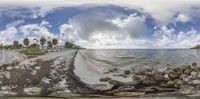 the 360 camera view shows a road and beach area with clouds in the background of a panoramic view