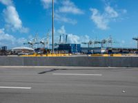 an empty parking lot filled with lots of buildings and trucks in the background of a cloudy blue sky