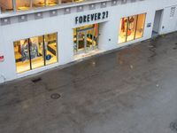 a store front is pictured with rain all around it on the ground below the sign