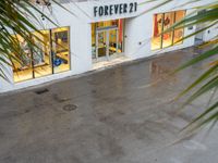 a store front is pictured with rain all around it on the ground below the sign