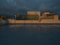 a building with lots of glass is shown on the street corner and cloudy sky is in the distance