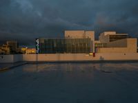 a building with lots of glass is shown on the street corner and cloudy sky is in the distance