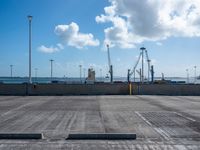 a empty parking lot under blue skies with several lights on poles and some construction equipment