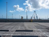 a empty parking lot under blue skies with several lights on poles and some construction equipment