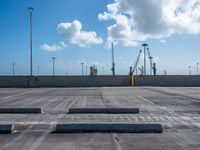 a empty parking lot under blue skies with several lights on poles and some construction equipment