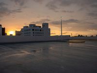 a parking lot with many parking spaces in the middle of it at sunset in front of large buildings and parking lights