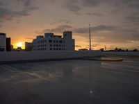 a parking lot with many parking spaces in the middle of it at sunset in front of large buildings and parking lights