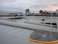 the view from a roof looking toward an urban setting with parking spaces and streetlights