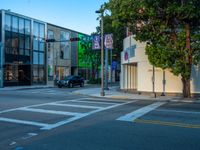 an empty street with a building near by onlookers and stoplights with signs