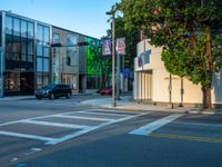 an empty street with a building near by onlookers and stoplights with signs