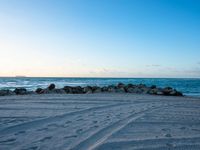 this is the ocean with waves coming in and sand on it, with a rock formation that looks like the shore break wall