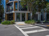 a zebra crossing on the street in front of a building with many different windows and plants