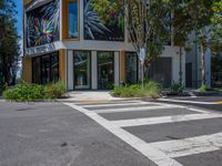 a zebra crossing on the street in front of a building with many different windows and plants