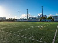 the sun shines on the empty field with the school building in the background in an urban setting