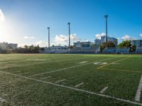 the sun shines on the empty field with the school building in the background in an urban setting