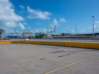 a empty parking lot with some trucks in the background and blue skies in the distance