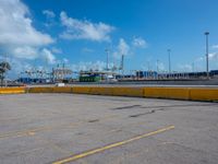 a empty parking lot with some trucks in the background and blue skies in the distance