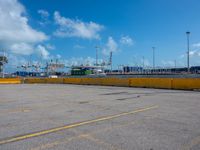 a empty parking lot with some trucks in the background and blue skies in the distance