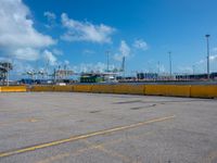 a empty parking lot with some trucks in the background and blue skies in the distance