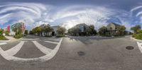 fish eye view of several buildings in front of a streetlight with blue sky and white clouds